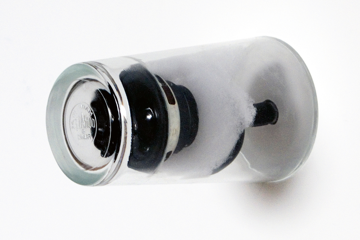 Drinking glass containing a speaker, attached to wall